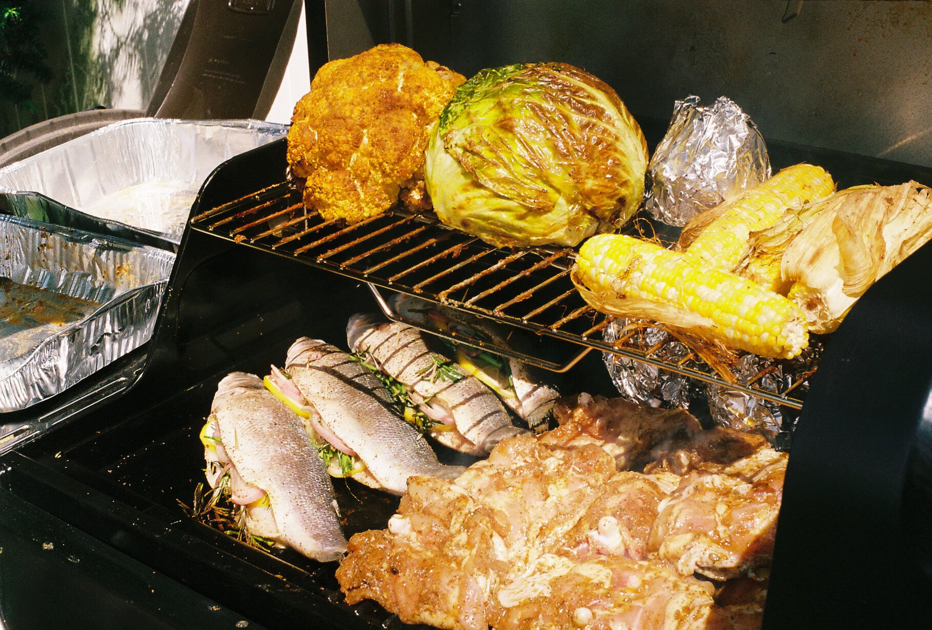 Grill loaded with whole fish, jerk chicken, and charred vegetables